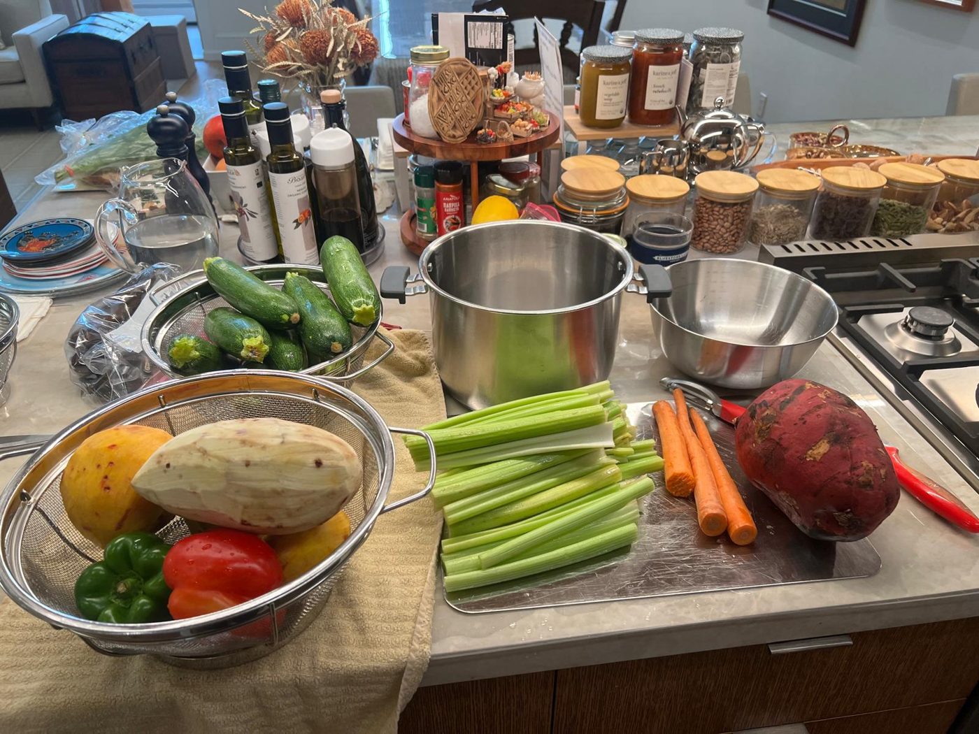Vegetables being prepped on a kitchen counter: cucumbers, celery, carrots, peppers and a sweet potato
